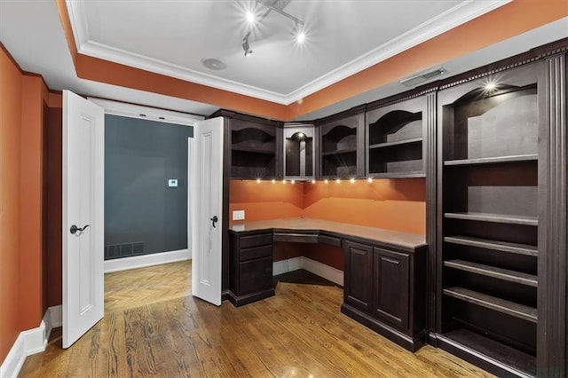 home office with hardwood / wood-style floors, built in desk, and crown molding