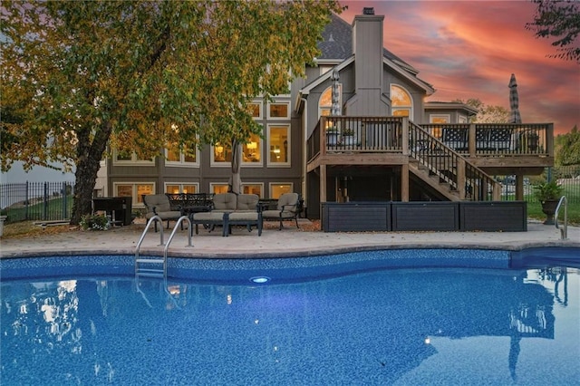 pool at dusk featuring a patio and a deck