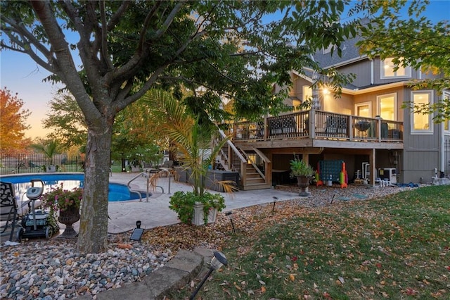 back house at dusk with a patio and a pool side deck