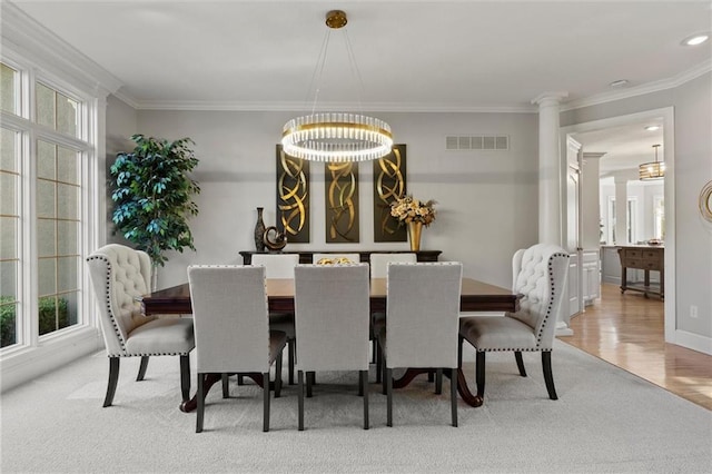 dining area featuring ornamental molding, wood-type flooring, decorative columns, and an inviting chandelier