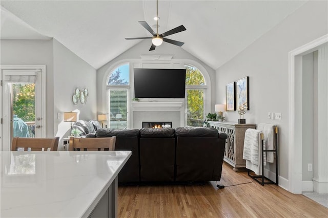 living room featuring ceiling fan, vaulted ceiling, and light hardwood / wood-style floors