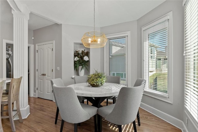 dining area featuring hardwood / wood-style floors, a notable chandelier, and ornate columns