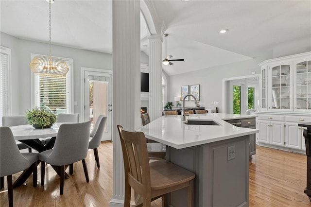 kitchen featuring sink, an island with sink, white cabinets, lofted ceiling, and ceiling fan with notable chandelier