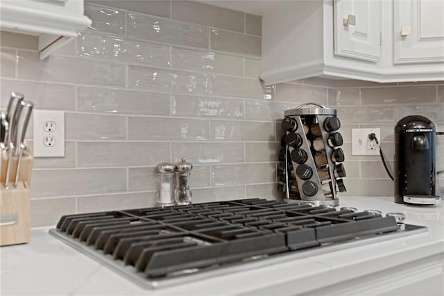 interior details with white cabinetry, stainless steel gas stovetop, and backsplash