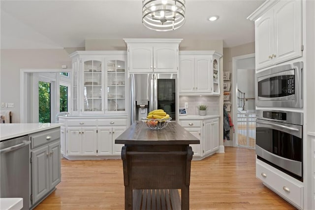 kitchen with appliances with stainless steel finishes, light hardwood / wood-style floors, and white cabinets