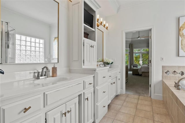 bathroom with tile patterned flooring, ornamental molding, ceiling fan, tiled tub, and vanity