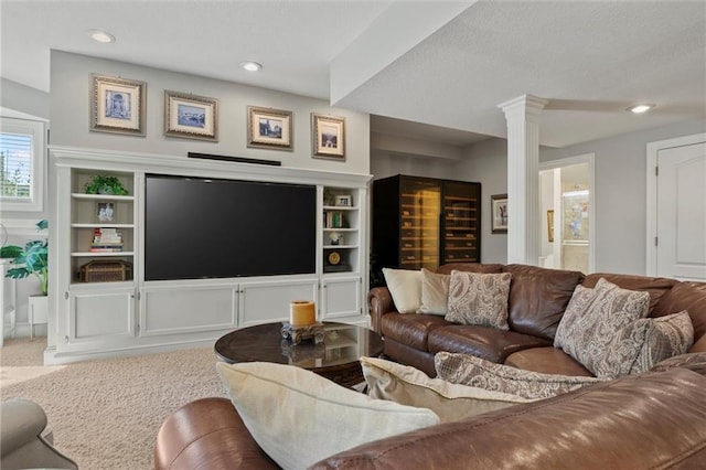 carpeted living room with built in features and ornate columns