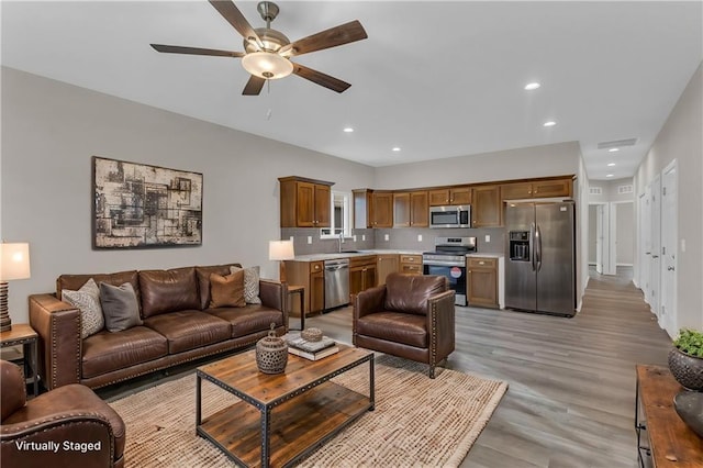 living room featuring ceiling fan, sink, and light hardwood / wood-style flooring