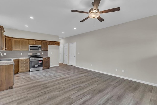 kitchen with ceiling fan, sink, light wood-type flooring, and appliances with stainless steel finishes