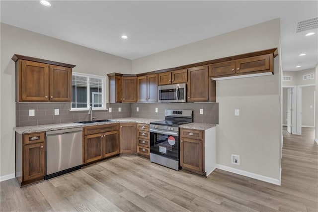 kitchen featuring light stone countertops, sink, light hardwood / wood-style floors, and appliances with stainless steel finishes