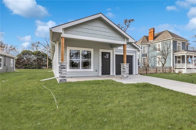 view of front of property featuring a front yard, a garage, and covered porch