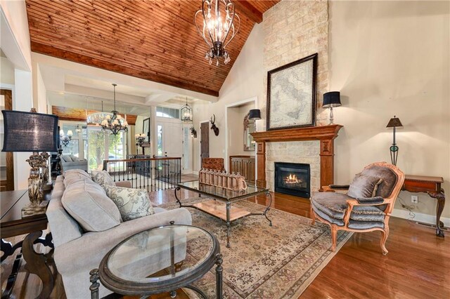 living room with a stone fireplace, high vaulted ceiling, a chandelier, wood ceiling, and hardwood / wood-style flooring