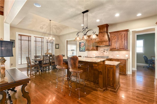 kitchen featuring custom exhaust hood, dark hardwood / wood-style floors, decorative light fixtures, and a chandelier