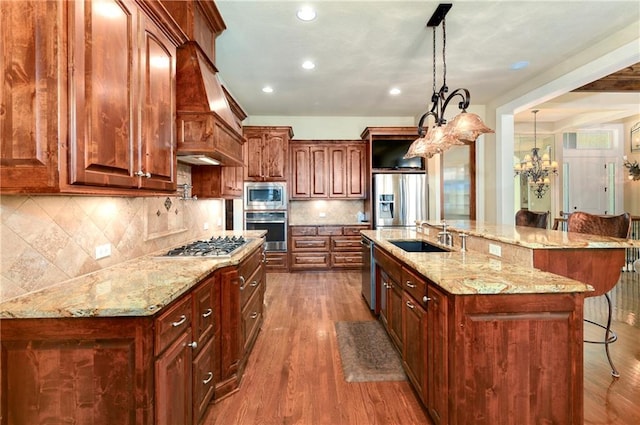 kitchen with a kitchen breakfast bar, hanging light fixtures, stainless steel appliances, and custom range hood