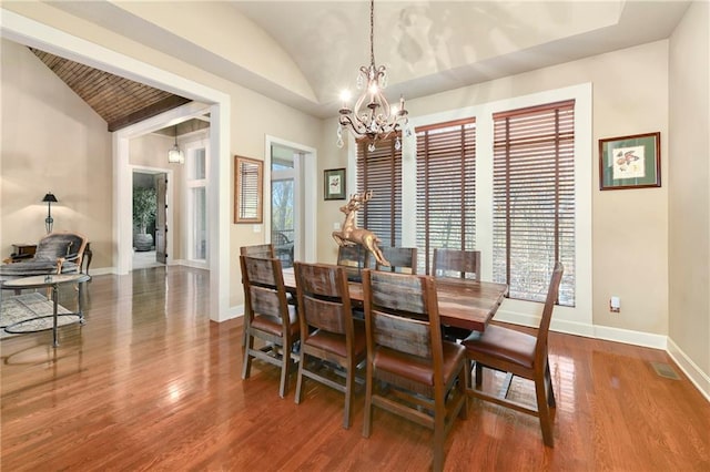 dining space with an inviting chandelier, wood-type flooring, and vaulted ceiling