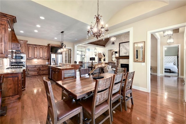 dining area with a notable chandelier, lofted ceiling, and hardwood / wood-style flooring