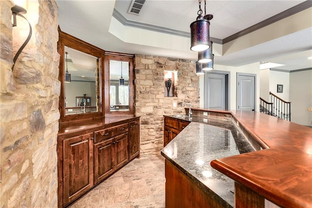 bar featuring sink, dark stone counters, a textured ceiling, decorative light fixtures, and ornamental molding