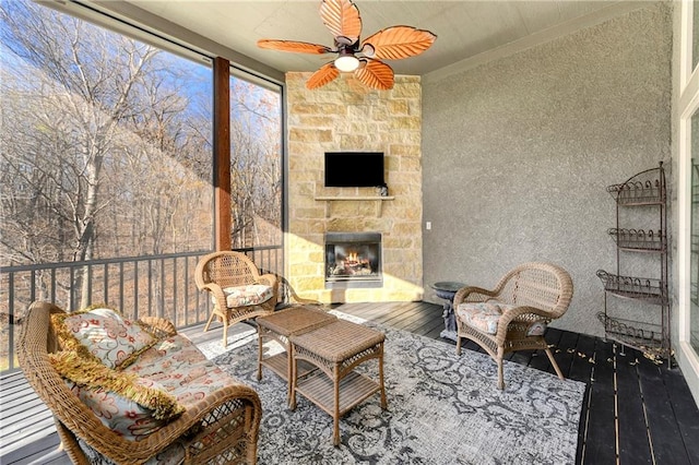 sunroom with an outdoor stone fireplace and ceiling fan