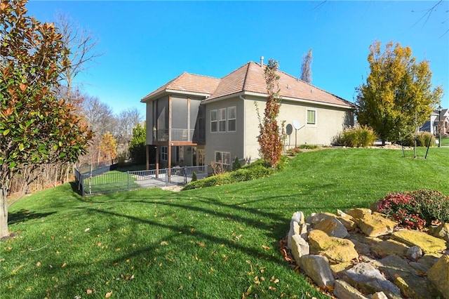 rear view of house with a sunroom, a patio, and a lawn