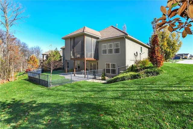 back of property featuring a lawn, a sunroom, and a patio