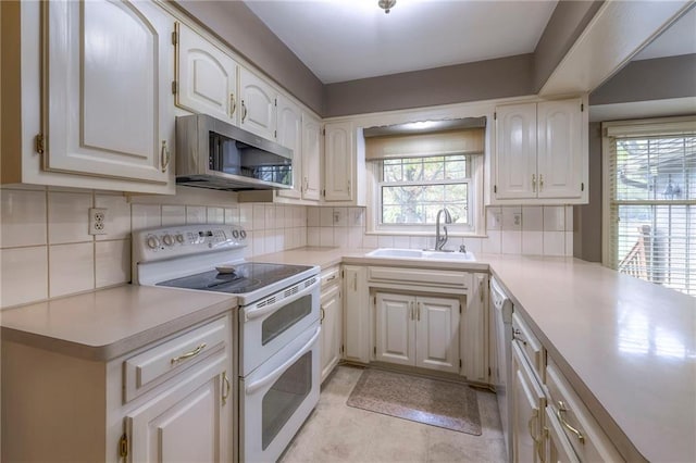 kitchen featuring white range with electric stovetop, tasteful backsplash, sink, and white cabinets