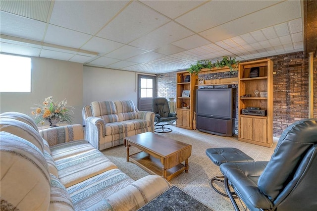 living room with a drop ceiling and brick wall