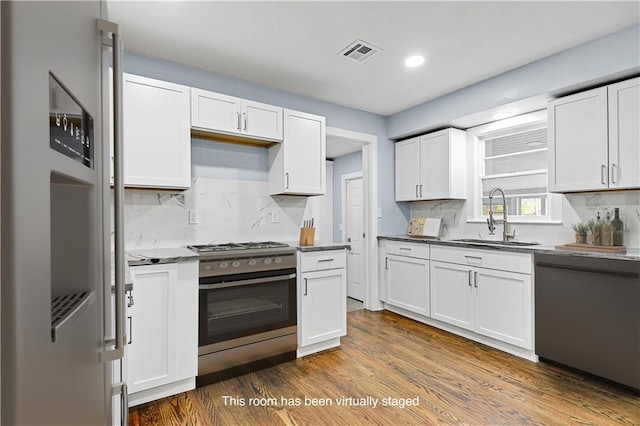 kitchen with stainless steel appliances, white cabinetry, dark hardwood / wood-style floors, and sink