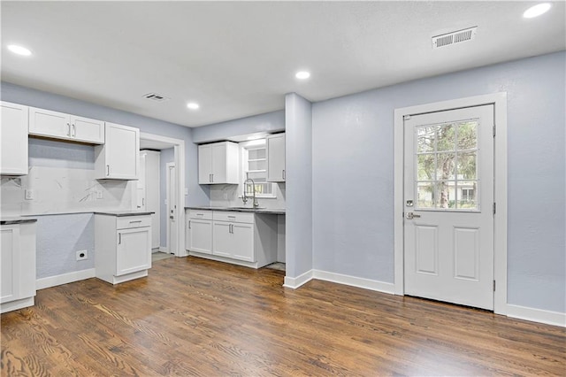 kitchen featuring backsplash, dark hardwood / wood-style flooring, white cabinetry, and sink