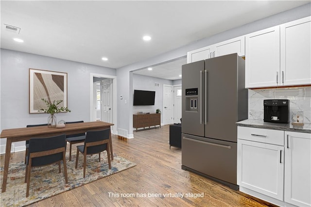 kitchen with decorative backsplash, stainless steel fridge, white cabinetry, and wood-type flooring