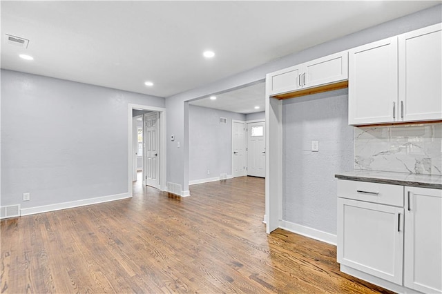 kitchen with decorative backsplash, white cabinets, and wood-type flooring