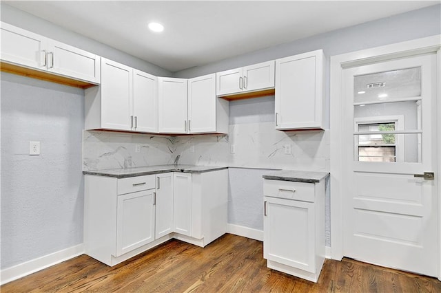 kitchen featuring dark stone countertops, decorative backsplash, white cabinets, and dark wood-type flooring