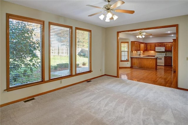 unfurnished living room with ceiling fan, light hardwood / wood-style floors, and sink