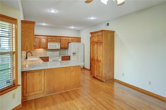 kitchen featuring kitchen peninsula, tasteful backsplash, white appliances, sink, and light hardwood / wood-style flooring