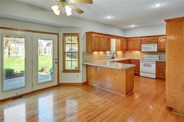 kitchen featuring kitchen peninsula, decorative backsplash, white appliances, and light wood-type flooring