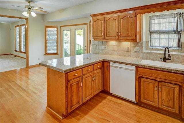 kitchen with dishwasher, sink, decorative backsplash, light wood-type flooring, and kitchen peninsula