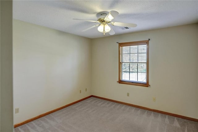 carpeted spare room featuring ceiling fan and a textured ceiling