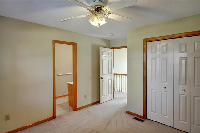 unfurnished bedroom featuring ceiling fan, a closet, light carpet, and a textured ceiling