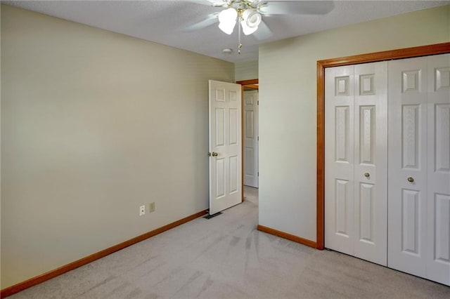 unfurnished bedroom featuring ceiling fan, a closet, and light colored carpet