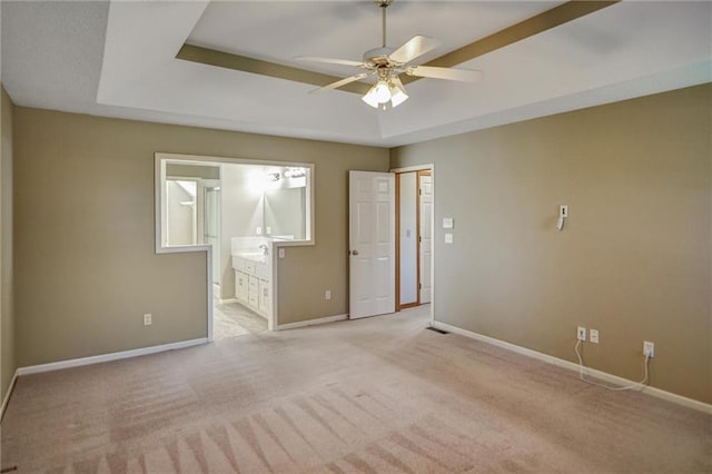 unfurnished room with a raised ceiling, ceiling fan, and light colored carpet