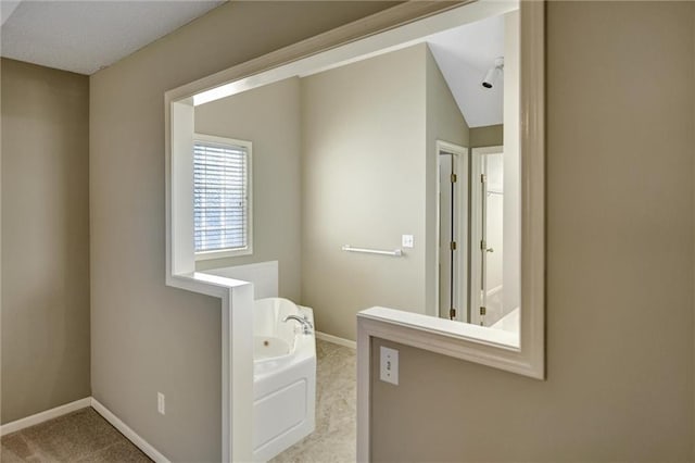 bathroom with a bathing tub and vaulted ceiling