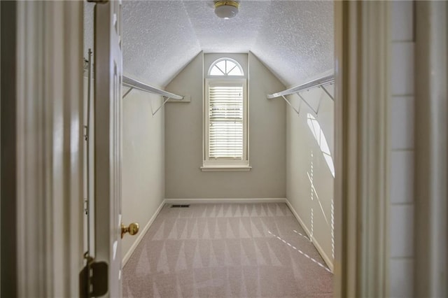 spacious closet with light colored carpet and lofted ceiling