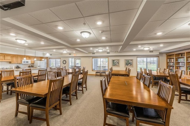 carpeted dining area with a paneled ceiling and beam ceiling