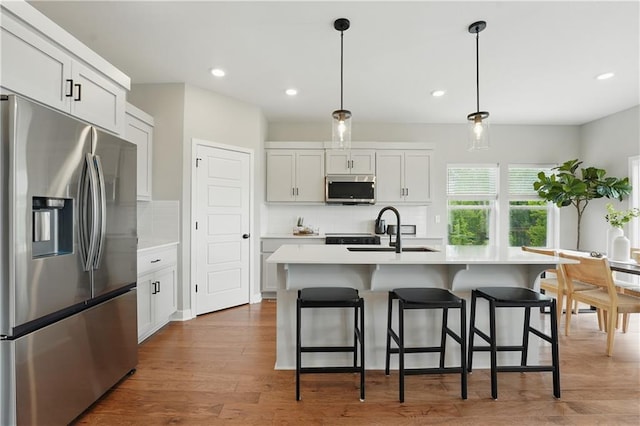 1024 Branchwood Ln, Raymore, MO 64083 - kitchen featuring stainless steel appliances, tasteful backsplash, light countertops, recessed lighting, and a kitchen bar