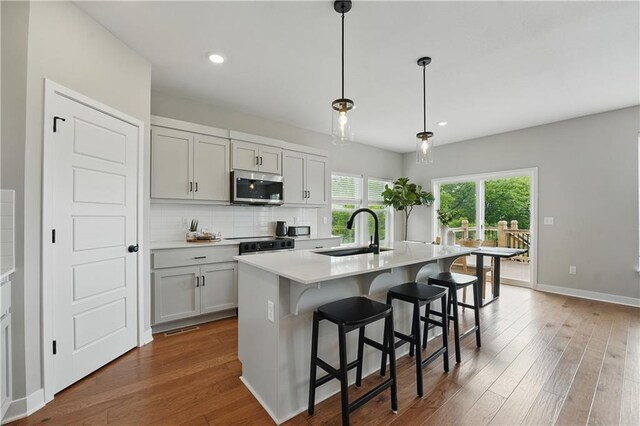 1024 Branchwood Ln, Raymore, MO 64083 - kitchen featuring stainless steel microwave, light countertops, backsplash, wood finished floors, and recessed lighting