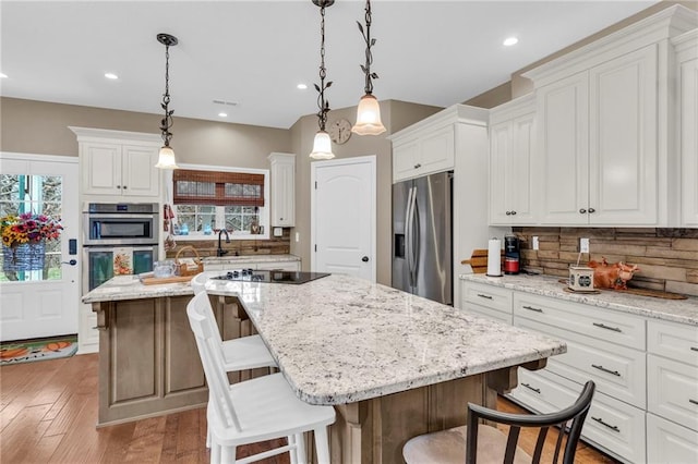 kitchen with a wealth of natural light, a kitchen island, appliances with stainless steel finishes, and white cabinets