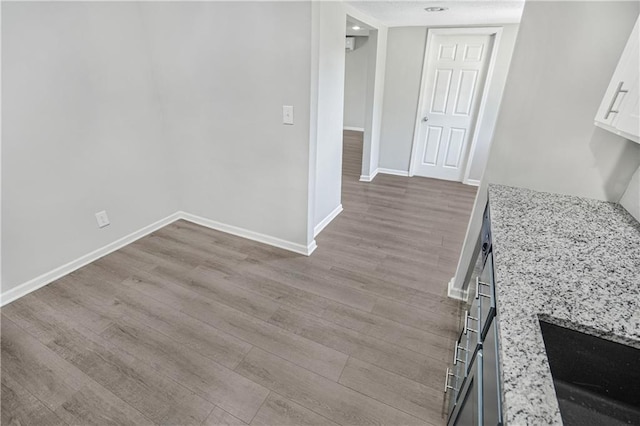 interior space featuring white cabinetry, light wood-type flooring, and light stone counters