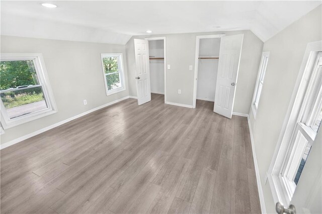 112 W Pine St, Drexel, MO 64742 - unfurnished bedroom with vaulted ceiling, two closets, baseboards, light wood-style flooring, and recessed lighting