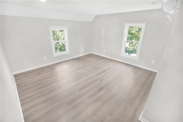 spare room with light hardwood / wood-style flooring, vaulted ceiling, and plenty of natural light