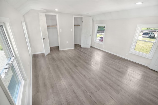 unfurnished bedroom with light hardwood / wood-style floors and lofted ceiling