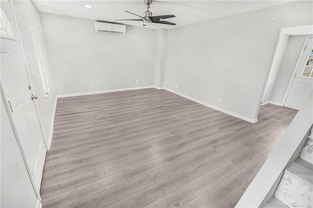 spare room with ceiling fan, a wall mounted air conditioner, and light hardwood / wood-style floors